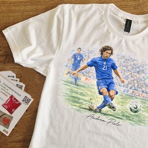 May include: White t-shirt featuring a soccer player in a blue uniform kicking a soccer ball. The shirt has the text "GERMANY 2006" and the player's signature. A stack of promotional cards is on the left.