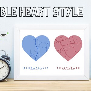 May include: A framed print featuring two heart-shaped maps, one blue and one red, with the text "DOUBLE HEART STYLE" at the top. The print includes the names Glenafallia and Tullylease. A black alarm clock and a vase of dried flowers are on the table.