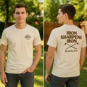 May include: A beige t-shirt with the text "CCO" on the front and "IRON SHARPENS IRON" with crossed golf clubs and "Proverbs 27.17" on the back. The shirt is worn by a person in front of a green background.