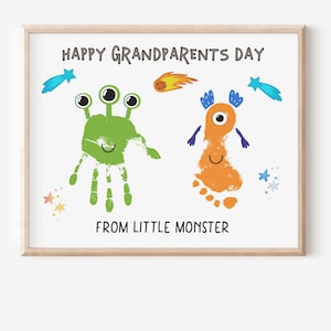 Pode incluir: Impressão emoldurada com o texto "HAPPY GRANDPARENTS DAY FROM LITTLE MONSTER". A obra de arte apresenta dois desenhos de monstros coloridos feitos com impressões de mãos e pés, com ilustrações de estrelas e cometas.