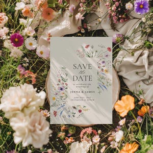 May include: A wedding invitation with the text "SAVE THE DATE" and a floral border. The invitation is on a white background and surrounded by colorful flowers. The text reads "to celebrate the wedding of JENNA & JAMES JUNE 21ST, 2025 invitation to follow."