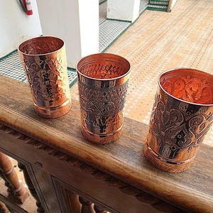 Close-up of the handcrafted scrollwork pattern on a copper drinking glass.