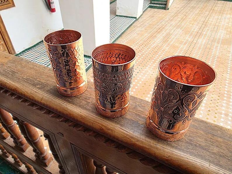 Close-up of the handcrafted scrollwork pattern on a copper drinking glass.