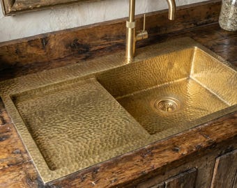 Fregadero de cocina de latón sin lacar con escurridor integrado, grifería artesanal de metal estilo granja.