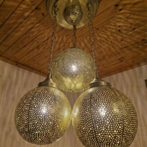 Warm light glowing through a perforated brass hanging lamp.