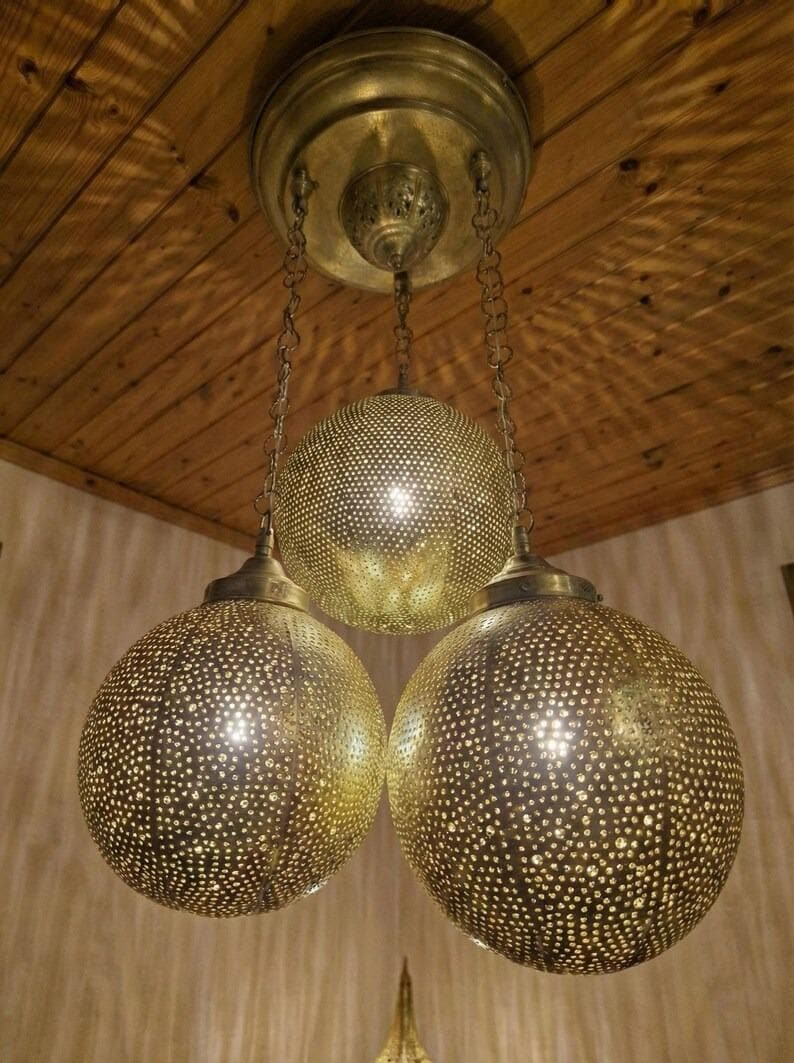 Warm light glowing through a perforated brass hanging lamp.