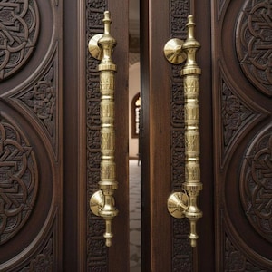 May include: Dark brown wooden doors with detailed carved patterns and gold-coloured handles. The doors are slightly open, revealing a glimpse of the interior. The handles are long and ornate. The doors are made of wood.