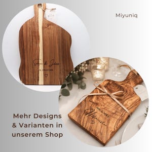 May include: Two wooden serving boards with handles. One board features the engraved text 'Sabrina & Julius 24. JANUAR 2026' with a heart. The other board is tied with a ribbon and engraved with 'MR. & MRS. Hofmeister' and a heart symbol.