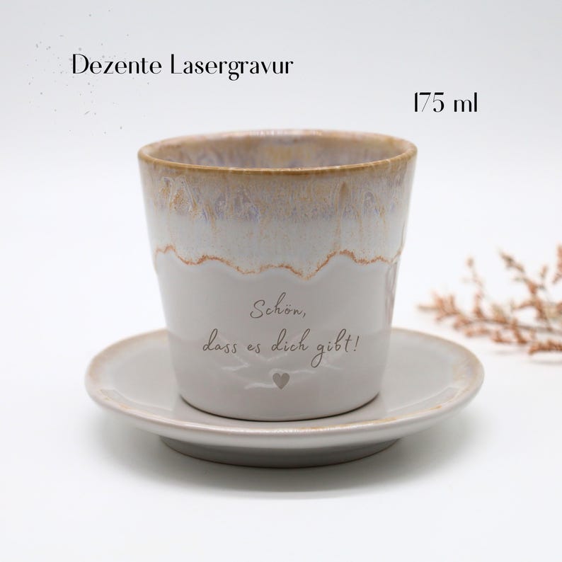 May include: A ceramic cup and saucer set. The cup is white with a light brown rim and a decorative wavy line. The cup has the text "Sch&ouml;n, dass es dich gibt!" and a heart. The cup holds 175 ml.