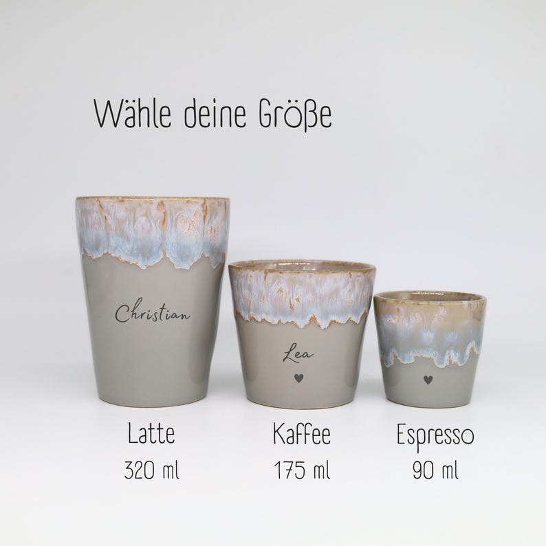 May include: Three ceramic cups with a grey base and a blue and white drip glaze rim. The cups are labeled Latte 320 ml, Kaffee 175 ml, and Espresso 90 ml. The text W&auml;hle deine Gr&ouml;&szlig;e is at the top. The cups feature the names Christian and Lea.