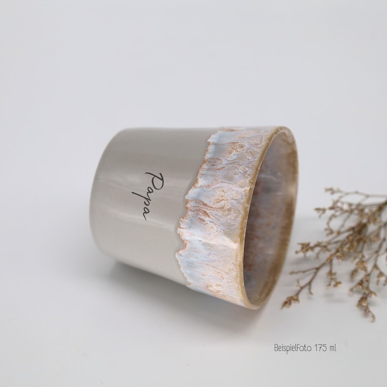 May include: A light gray ceramic mug with the word Papa printed in black script. The rim features a textured, dripped glaze effect in shades of white, tan, and light blue. The mug has a capacity of 175 ml as indicated by the text in the corner.