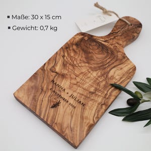 May include: A rectangular wooden serving board with a handle, featuring a natural wood grain pattern. It is engraved with the text HANNA + JULIAN 8. NOVEMBER 2025 and a small leaf icon. The board measures 30 x 15 cm and weighs 0.7 kg.