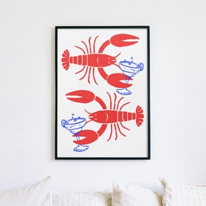 Pu&ograve; includere: Una stampa artistica da parete incorniciata raffigurante due aragoste rosse orientate in direzioni opposte, ognuna delle quali tiene un bicchiere da margarita blu con una fetta di lime. La stampa ha uno sfondo bianco e una cornice nera sottile.