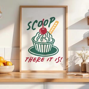 Pu&ograve; includere: Una stampa artistica da parete incorniciata con un'illustrazione grafica di una coppa gelato in una ciotola con una ciliegia sopra e un wafer. Il testo SCOOP THERE IT IS! &egrave; stampato in lettere verde scuro e rosse sopra e sotto il dessert.