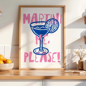 Pu&ograve; includere: Una stampa artistica da parete incorniciata con un'illustrazione a linee blu di un bicchiere da martini con una fetta di agrume. Il testo "MARTINI ME, PLEASE!" &egrave; stampato in un carattere rosa audace e scritto a mano su sfondo bianco.