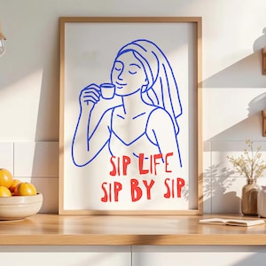 Pu&ograve; includere: Una stampa artistica da parete incorniciata con un disegno a linee blu di una persona con un asciugamano avvolto intorno alla testa, che tiene in mano una tazzina. Sotto l'illustrazione, il testo rosso recita SIP LIFE SIP BY SIP.
