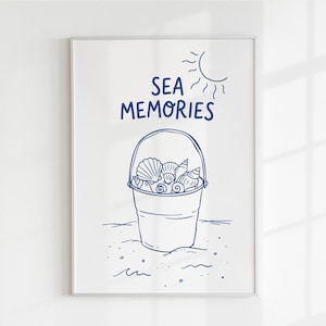 May include: A framed print featuring a blue line drawing of a bucket filled with seashells. The words "SEA MEMORIES" are above the bucket, with a sun illustration in the upper right corner. The artwork is on a white background.