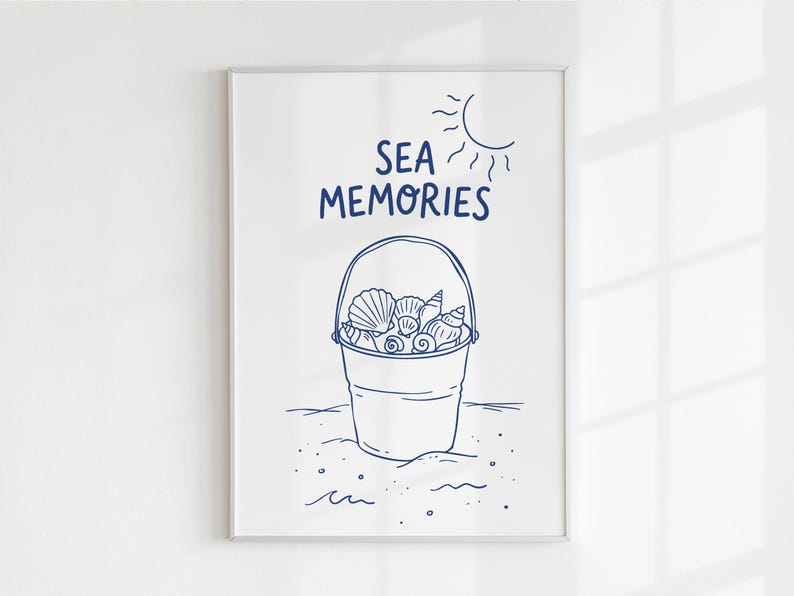 May include: A framed print featuring a blue line drawing of a bucket filled with seashells. The words "SEA MEMORIES" are above the bucket, with a sun illustration in the upper right corner. The artwork is on a white background.