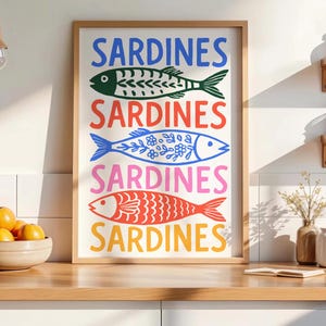 Pu&ograve; includere: Una stampa da parete rettangolare incorniciata che presenta la parola SARDINES in quattro colori diversi, alternata a quattro illustrazioni di pesci stilizzati. I pesci sono colorati di verde scuro, blu con motivi floreali, rosso e giallo.