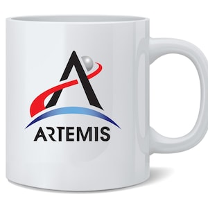 May include: White ceramic mug featuring the Artemis logo. The logo includes a black and silver A-shaped design with a red and blue arc, and the word "ARTEMIS" in black. The mug has a curved handle.