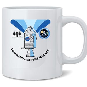 May include: White ceramic mug featuring a blue and white graphic of the Apollo Command and Service Module, NASA logo, and the text "COMMAND AND SERVICE MODULE." The mug also includes a depiction of three astronauts.