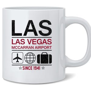 May include: White ceramic mug with the text "LAS LAS VEGAS MCCARRAN AIRPORT" in black and red. Includes icons of an airplane, globe, and suitcase. The text "SINCE 1941" is also present. A perfect souvenir.