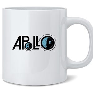 May include: White ceramic mug with a curved handle. The mug features the word "APOLLO" in black, with a graphic of the Earth and a blue and black graphic of the moon with the number "11".