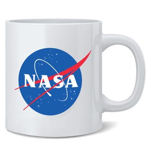 May include: A white ceramic mug featuring the blue, white, and red NASA logo printed on the front. The logo consists of a blue circle with white stars, a white orbital path, and the white text NASA crossed by a red vector shape.