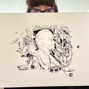 May include: Black and white abstract art print featuring a central human profile, surrounded by flowing, organic shapes. The artwork includes a pipe and a sphere, with intricate details and shading. The print is held by a person.