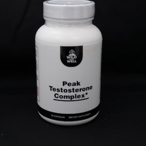 May include: A white plastic bottle with a white lid. The label reads "Peak Testosterone Complex" with the "Wild Well" logo. The bottle contains 90 capsules and is a dietary supplement.