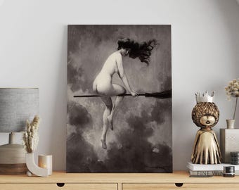 Pode incluir: Uma impressão a preto e branco de uma figura nua montada numa vassoura contra um fundo nublado. A obra de arte é exibida acima de um armário de madeira, juntamente com uma lâmpada, objetos decorativos e uma figura dourada.