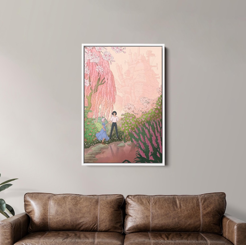 May include: A framed art print depicts a romantic scene with two figures in a garden. The artwork features a soft color palette of pinks, greens, and blues, with a castle in the background. The print is displayed above a brown leather sofa.