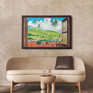 May include: A framed artwork depicts a vibrant landscape scene viewed through an open window. The artwork showcases a village with red-tiled roofs, green hills, and snow-capped mountains under a blue sky with fluffy clouds. A hot air balloon floats in the sky.
