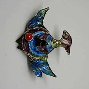 Könnte beinhalten: Eine farbige Fischbrosche aus Emaille mit einem roten Auge, blauen, grünen, violetten und goldenen Akzenten.