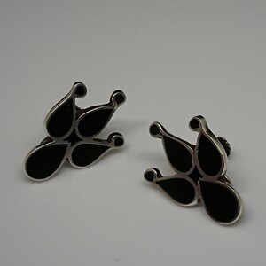 May include: A pair of black and silver earrings with a teardrop design.