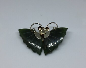 May include: A green jade butterfly brooch with gold accents. The butterfly has detailed wings and a delicate design.