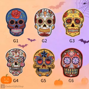 Peut inclure: Six écussons de crânes de sucre colorés avec des motifs floraux et géométriques complexes. Chaque crâne présente une palette de couleurs unique, notamment le bleu, le jaune et le rouge, avec des détails tels que des roses et des étoiles. Les écussons sont étiquetés G1 à G6.
