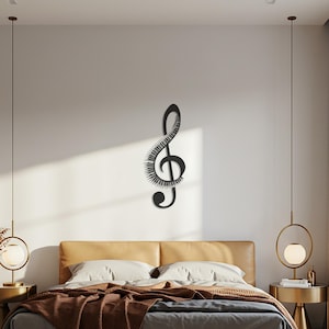 May include: A black metal treble clef wall art piece. The musical symbol is mounted on a white wall above a bed. The clef has a unique design with a series of lines and curves, adding a modern touch to the room.