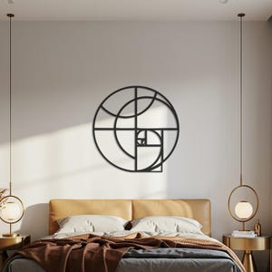May include: Black metal wall art depicting the Fibonacci sequence. The circular design features intersecting lines and curves. It's mounted on a white wall above a bed with a brown headboard and bedding. The artwork is approximately 60 cm in diameter.