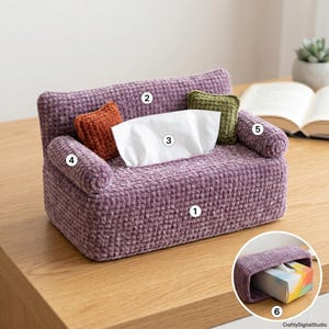 Puede incluir: Una funda de ganchillo para caja de pañuelos con forma de sofá en miniatura, de color morado, con respaldo alto, dos reposabrazos redondeados y dos cojines cuadrados pequeños en naranja y verde. Un pañuelo blanco asoma por el centro. Un recuadro muestra la funda.