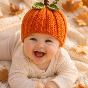 Può includere: Un cappello all'uncinetto color arancione brillante progettato per assomigliare a una zucca, caratterizzato da una trama a coste verticali, un piccolo stelo marrone sulla parte superiore e due foglie verdi con un viticcio riccio come dettaglio.