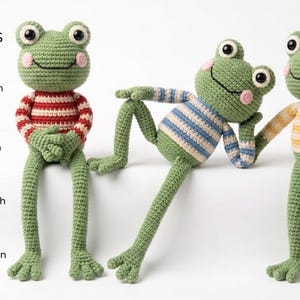 May include: Three crocheted green frog dolls with large black and white eyes and pink cheeks. The frogs wear striped sweaters in red, blue, and yellow. Text on the left reads: PATTERN LANGUAGES AVAILABLE: English US, French, Spanish, German.