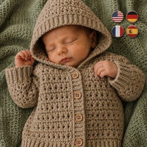 May include: A beige hooded cardigan featuring a textured crochet stitch pattern, long sleeves with ribbed cuffs, and a front button closure with four light brown wooden buttons. The garment has a pointed hood and a ribbed hem at the bottom edge.