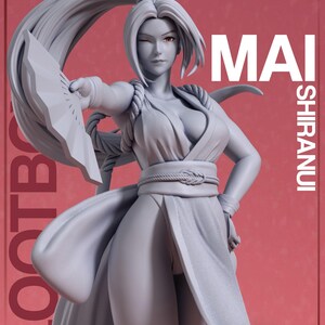 Puede incluir: Figura gris de un personaje femenino, guiñando un ojo, sosteniendo un abanico. La figura lleva un atuendo estilo kimono con un cinturón de cuerda. El texto "MAI SHIRANUI" se muestra en el lado derecho de la imagen.