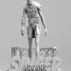 May include: A grayscale figurine of a character from the video game "Arcane: League of Legends." The figure is posed with a mask, wrapped in bandages, and wearing a utility belt. The base of the figurine features the game's title.