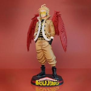 Pode incluir: Uma figura detalhada do personagem Hawks da série de anime My Hero Academia. A figura está em uma pose dinâmica, vestindo uma jaqueta bege com gola de pele branca, calças combinando e botas pretas. A figura tem grandes asas vermelhas e óculos amarelos.