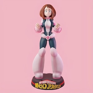Könnte beinhalten: Figur einer weiblichen Anime-Figur in einem dunkel türkis-weißen Body mit rosa Akzenten. Die Figur hat braune Haare und steht auf einer schwarzen Basis mit japanischem Text und den Worten "My Hero Academia". Der Hintergrund ist rosa.