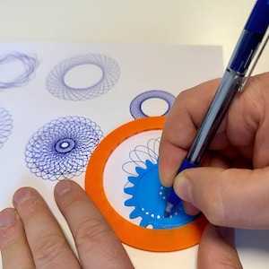 Pode incluir: Uma caneta azul é usada para criar padrões geométricos intrincados em papel branco. Uma ferramenta de espirógrafo azul e laranja é usada para criar os desenhos. Vários desenhos concluídos são visíveis.