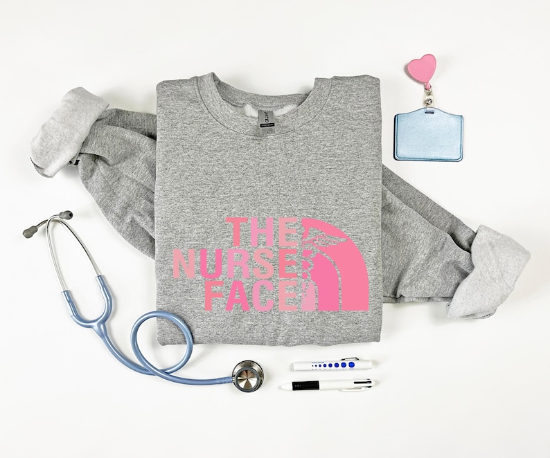 a gray sweatshirt with a pink logo, a stethoscope, a name tag, a pen, and a heart-shaped charm.