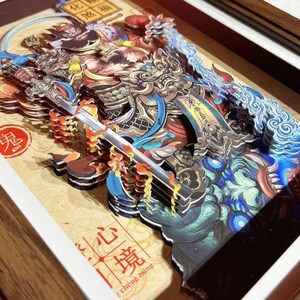 May include: A detailed, multi-layered paper art piece depicting a warrior figure with a sword, in shades of blue, gold, and red. The artwork is framed in a wooden frame and features Chinese characters and symbols. The word "KUI" is visible.